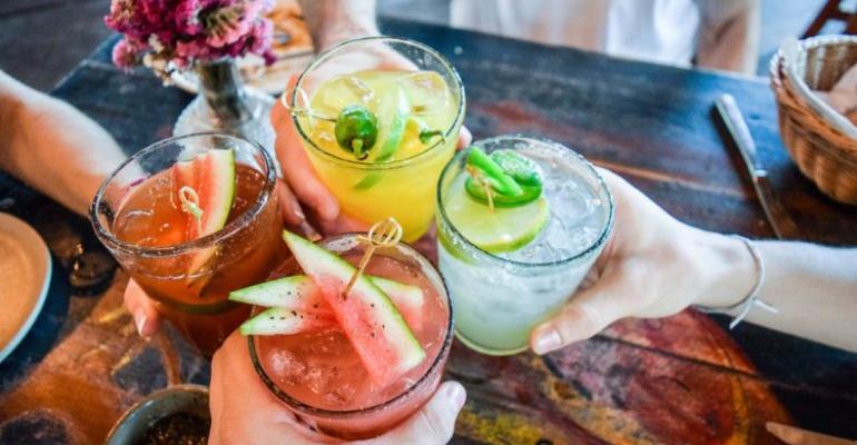 pessoas brindando com copos de bebidas não alcoólicas coloridas